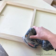 a person using a sanding machine on a piece of wood that is being framed