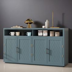 a blue cabinet with two doors and some cups on top of it in front of a gray wall