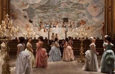 a group of women standing in front of a wall with chandeliers on it