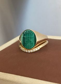 Malachite Coat of Arms Signet Ring that can be personalized with your desired Family Crest design and a diamond band set. A handmade piece that has been brought to life with the combination of fine goldsmith techniques and the latest technology. A beautiful green gemstone signet ring with a diamond band set for a complete look. ◾ Band - Natural Diamonds: 0.055ct VS-G-H ◾ Size of Signet Ring Gemstone: 1.2 x 1cm A variety of gemstones to choose from. We can place onyx, lapis lazuli, and more! 📩 L Heirloom Emerald Signet Ring As Gift, Luxury Engraved Green Rings, Green 14k Stamped Signet Ring As Gift, Green 14k Stamped Signet Ring, Perfect For Gifts, Gift Green Signet Ring Stamped 14k, Gift Green 14k Stamped Signet Ring, Heirloom Green Engraved Rings, Classic Green Engraved Signet Ring, Green Oval Engraved Rings