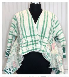 This easy fitting short kimono sleeve shrug jacket is a must have for your wardrobe. It was made using a collage of beautiful pieces of vintage chenille.  The squares of chenille are a mixture of cream amid green and dark green thick and soft chenille. These pieces were laid out and stitched on a complimentary colored flowered cotton vintage sheet, giv8ng the jacket a quilted effect. The chenille had served its useful life as bed spreads and was fussy cut to make this one of a kind jacket. The jacket is soft and warm and is easy fitting.  This French fold pattern is considered zero waste. And the crop jacket style is very size forgiving. It will fit Medium up to a 2 X easily. With its no closure side wrap front it can be styled many ways.  Notice the side panels can be wrapped several ways Spring Cotton Patchwork Cardigan, Spring Cotton Cardigan With Patchwork, Fitted Green Spring Kimono, Green Patchwork Kimono For Spring, Spring Cotton Fitted Shrug, Fitted Cotton Spring Shrug, Fitted Cotton Shrug For Spring, Spring Fitted Cotton Shrug, Spring Cotton Kimono With Patchwork