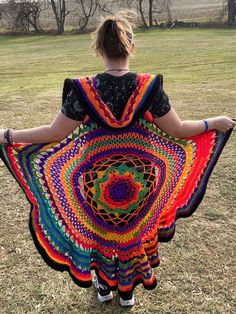 a woman is holding a colorful crocheted shawl