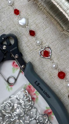 a pair of scissors sitting on top of a table next to some beads and chains