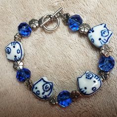 Hand Crafted Blue And White Silvertone Kitty Bracelet Cute Cobalt Blue And White Ceramic Kitty Beads With Flowers On Their Foreheads Alternate With Faceted Blue Glass Beads And Silvertone Flower Spacer Beads. Toggle Clasp Approximately 7 3/8 Inches Adorable Bracelet For Kitty Lovers! Designed And Handcrafted By Aj_nelly! Ladybug Redesign, Clay Charm Bracelet, Bracelet Supplies, Ceramic Beads Bracelet, Clay Keychain, Bracelet Inspo, Bracelet Cute, Fotos Aesthetic, Clay Stuff