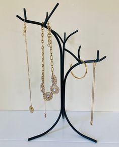 three pairs of necklaces are hanging on a tree branch with chains attached to it