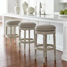 three stools sitting on top of a wooden floor in front of a countertop