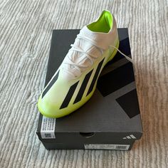 a pair of adidas soccer shoes sitting on top of a shoe box in the middle of a bed