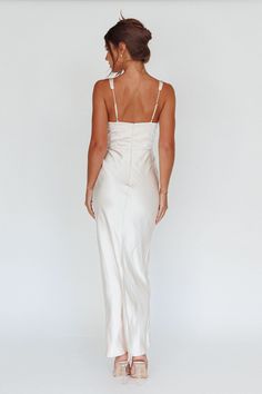 the back of a woman wearing a white dress with spaghetti straps and high slits