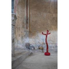 a red sculpture sitting in the middle of a room next to a stone wall and doorway