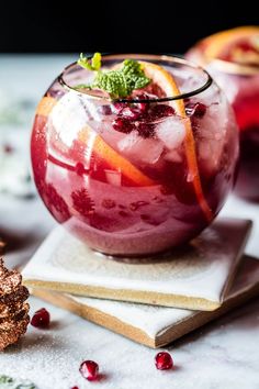 two glasses filled with fruit and garnish on top of napkins next to pine cones