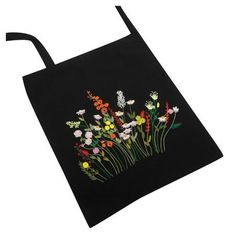 a black tote bag with colorful flowers on the front and side, embroidered onto it