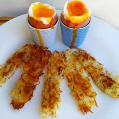 there are eggs in cups on the plate and one egg is cut up into smaller pieces