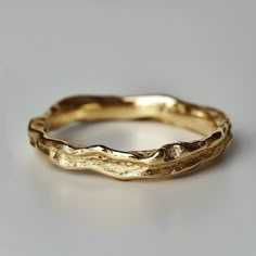 a close up of a gold wedding ring on a white surface with no one around it