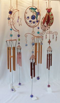 a group of wind chimes hanging from a white wall in front of a white backdrop