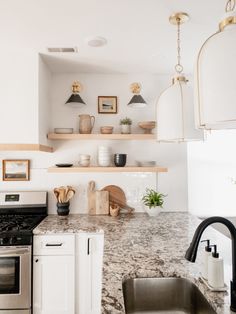 a kitchen with marble counter tops and white cabinets, open shelves above the stove top