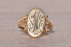 The Rouge: Vintage Signet Ring in Yellow Gold. This elegant ring features an elongated oval top oriented North to South, adorned with a hand-engraved monogram at the center, which can be customized with your initials for an additional $250 upon request. Flanking the center, patterned double split shanks complete the look, adding depth and dimension to the design. Crafted in 14 karat yellow gold, the ring exudes warmth and sophistication. Currently sized at 3, it can be adjusted to fit any finger Antique Oval Signet Ring With Polished Finish, Victorian Oval Signet Ring With Polished Finish, Elegant 14k Gold Engraved Initials Ring, Elegant 14k Gold Initial Ring With Engraving Option, Classic Oval Signet Ring For Formal Occasions, Victorian Style Engraved Ring With Polished Finish, Victorian Engraved Signet Promise Ring, Antique Oval Hallmarked Signet Ring, Antique Engraved Ring With Polished Finish For Formal Occasions