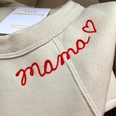 a sweater with the word mama written on it and a heart drawn in red thread