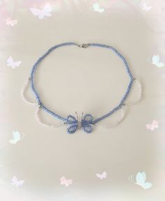 a blue and white beaded necklace with two butterflies on the front, sitting on a butterfly background