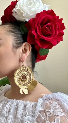 a woman with flowers in her hair wearing large gold earrings and a red rose behind her ear