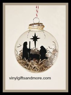 a glass ornament with two black nativity figures in the center and a star hanging from it