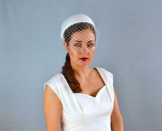 "This is a classic bridal pillbox hat covered with dupioni silk and finished with a bow. The pillbox hat is completely hand made using traditional millinery techniques and a lot of skill and attention to detail. The base for this hat is hand blocked using buckram and other materials to give the headpiece it's unique shape and smooth surface. The base is then covered with high quality dupioni silk. The hat is adorned with silk bow and comes with a removable birdcage veil (optional). This hat is f Fitted Cream Cloche Hat For Wedding, White Fitted Hats For Vintage Events, Classic Fitted Cloche Hat For Wedding, Classic White Fascinator, White Cloche Hat With Short Brim For Wedding, White Short Brim Cloche Hat For Weddings, Elegant White Fitted Bonnet, Classic Top Hat With Short Brim For Wedding, Classic Short Brim Top Hat For Wedding