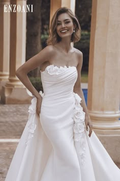 a woman in a white wedding dress posing for the camera with her hands on her hips