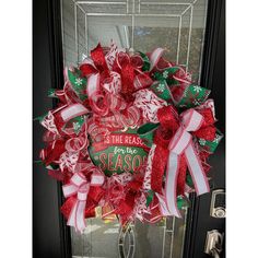 a christmas wreath on the front door with red and green ribbons hanging from it's side