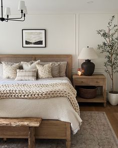 a bedroom with a bed, nightstands and pictures on the wall above it is decorated in neutral colors