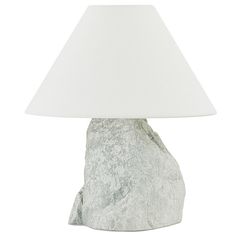 a lamp that is sitting on top of a rock with a white lampshade