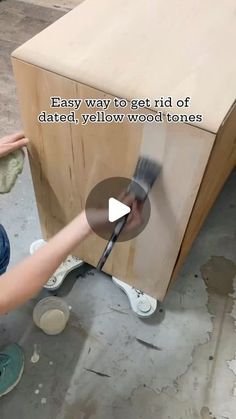 a person is using a paintbrush to paint a wooden cabinet