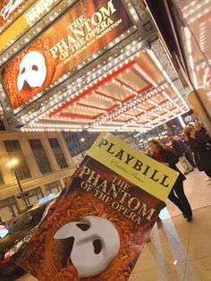 there is a sign that says playbill on the side of a building with marquee lights in the background