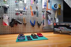 a pegboard with some cars on it next to a wall mounted tool holder and magnets