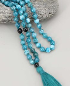 108 beads meditation mala is made of blue Apatite, a stone that fosters clarity and insight, clearing away confusion to give you that “Eureka!” moment. Accented with black onyx beads for strength on your journey. Intended for counting and chanting, you use a mala simply by moving through its beads one by one. Bead size: 6mm Individually Knotted between each bead Made of blue appetite and black onyx beads Turquoise green shade cotton tassel Bead Configuration: 6 BA + 1 Onyx + 94 BA + 1 Onyx + 6 B Meditation Beads Mala, Eureka Moment, Buddha Groove, Mala Meditation, 108 Bead, Turquoise Green, Blue Apatite, Onyx Bead, Mala Beads