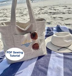 a tote bag sitting on top of a beach next to a hat and sunglasses