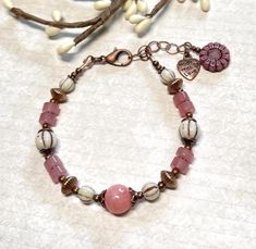 Pretty boho bracelet with a bit of vintage style vibes. I have created this beauty using a pink Quartzite stone bead as the focal, Strawberry Quartz gemstone rondelles, white Czech glass melon beads with a brown wash, and antique copper accents throughout.  Can go from jeans to dressy, and is a wonderful gift idea! The bracelet has an extender chain, and closes with a lobster clasp.  The extender chain is finished with a copper heart charm, and a dangling Czech glass dusty rose sunflower bead. B Pink Quartzite, Pink Beaded Bracelet, Rose Quartz Bracelet Beads, Pink Beaded Bracelets, Copper Heart, Bohemian Bracelet, Copper Accents, Rose Quartz Bracelet, Pink Beaded