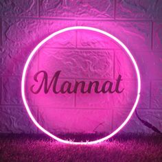 a neon sign that says manat on it in front of a pink brick wall