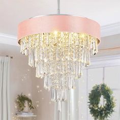 a pink chandelier hanging from a ceiling in a living room with wreaths