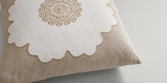 a white and beige pillow with an intricate design on it