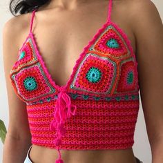 a woman wearing a pink crochet top with green and blue beads on it