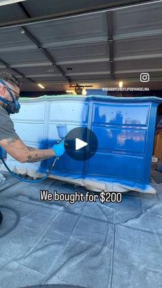 a man is painting the side of a blue truck with a sprayer on it