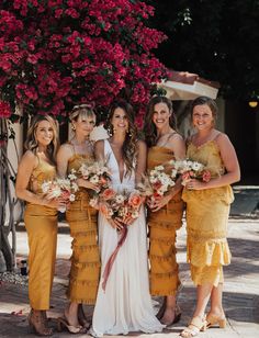 a group of women standing next to each other holding bouquets in their hands and smiling