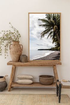 a wooden table topped with a vase next to a painting on top of a wall