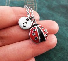 a ladybug necklace with the letter c on it