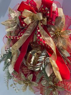 a red and gold christmas wreath with bells on it's front door hanger