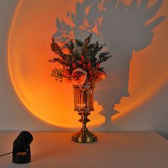 a vase filled with flowers sitting on top of a table next to a light bulb