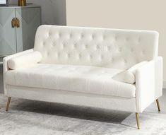 a white couch sitting on top of a rug in front of a wall mounted cabinet