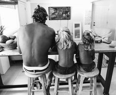 three people sitting on stools at a kitchen table