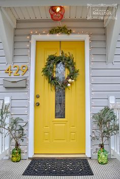 a yellow front door with wreaths on it