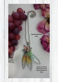 a necklace with an image of a butterfly on it and some grapes in the background