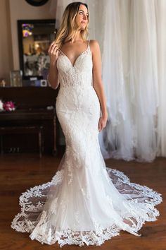 a woman in a white wedding dress standing on a wooden floor with her hands behind her back